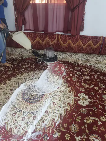 A rotary machine washing a majlis carpet, with wash foam on the rug